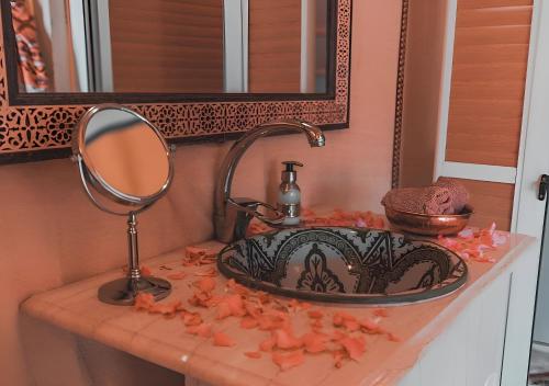 a bathroom sink with a mirror and orange flowers on a counter at Merzouga Lovely Luxury Camp in Merzouga