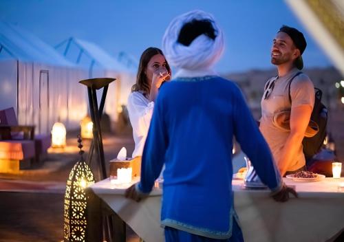 a group of people standing around a table with candles at Merzouga Top Desert Camp in Merzouga