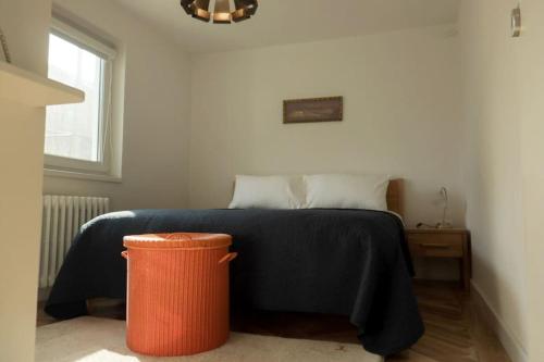 a bedroom with a bed with a black blanket and a trash can at A lovely flat in Visoko in Visoko
