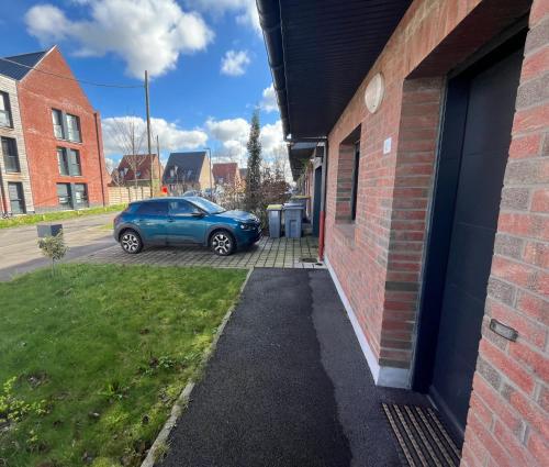 une voiture bleue garée à côté d'un bâtiment en briques dans l'établissement Le cottage au bord de la Lys à 20 min de Lille, à Frélinghien
