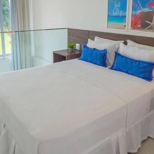 a large white bed with blue pillows in a bedroom at The Coral Beach Resort by Atlantica in Trairi