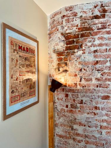 a brick wall in a room with a picture on the wall at Le Cocon Forézien - RDC - Proche gare et centre - Wifi in Feurs