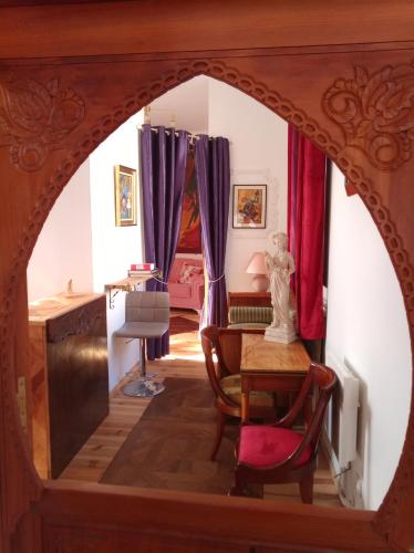 une porte cintrée donnant sur une chambre avec des rideaux violets dans l'établissement Gîte groupe cycliste via rhona Les Capucines, à Saint-Vallier