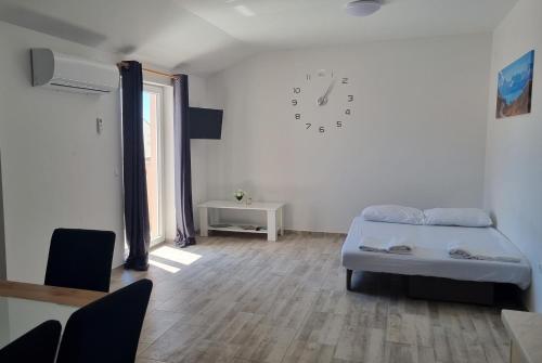 Apartment Diana - Novalja في نوفاليا: غرفة نوم بسرير وساعة على الحائط