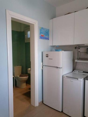 a kitchen with a white refrigerator and a toilet at Studio Blue Sky in Tripiti