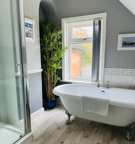 a white bath tub in a bathroom with a window at Bettys in Hunstanton