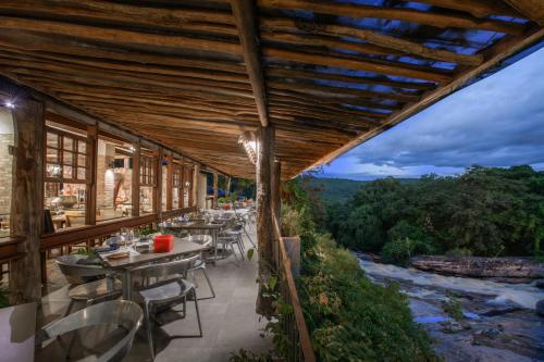 an outdoor patio with tables and chairs and a river at Hotel Canto das Águas - Roteiro de Charme in Lençóis
