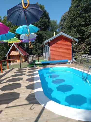 uma piscina com guarda-sóis e uma casa em Taćina i Dokina kolibica em Arandjelovac