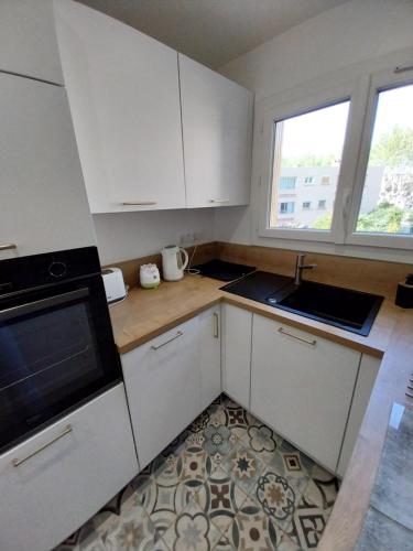 une cuisine avec des armoires blanches, un évier et une fenêtre dans l'établissement Appartement à 300m de la plage, à Fréjus