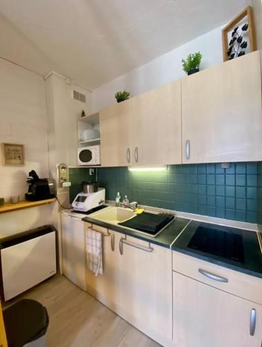une cuisine avec des armoires blanches et un évier dans l'établissement Appartement Au plaisir - Front de neige, Antarès, à Villarembert