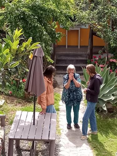 three women standing next to a bench and an umbrella at Hostal Maria Casa in La Serena