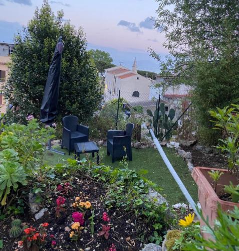 a garden with two chairs and an umbrella at Caieta: la casa nella roccia in Gaeta