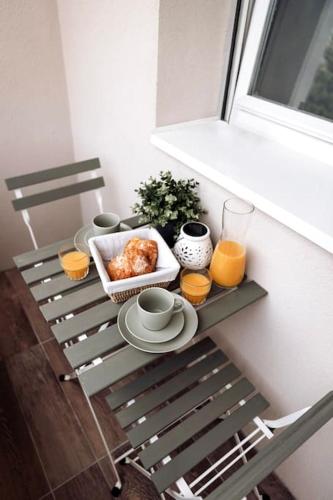 a table with a tray of food and orange juice at Royale Lumineux Jacuzzi Parking privé in Mulhouse