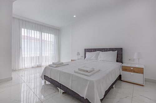 a white bedroom with a large bed and a window at NEAR BY THE LAND OF LEGENDs , PRİVATE POOL , VİLLA LARİSA in Belek