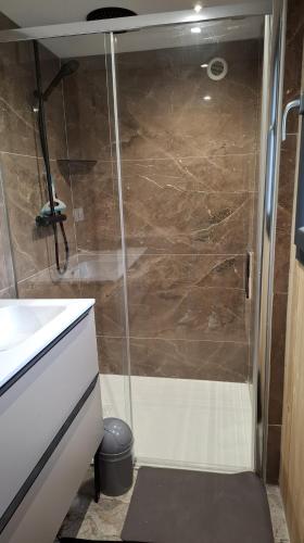 une douche avec une porte vitrée dans une salle de bain dans l'établissement Les Chalets en Ruynes, à Ruynes-en-Margeride