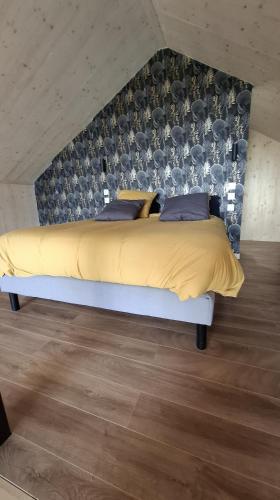 une chambre avec un grand lit jaune avec un mur dans l'établissement Les Chalets en Ruynes, à Ruynes-en-Margeride