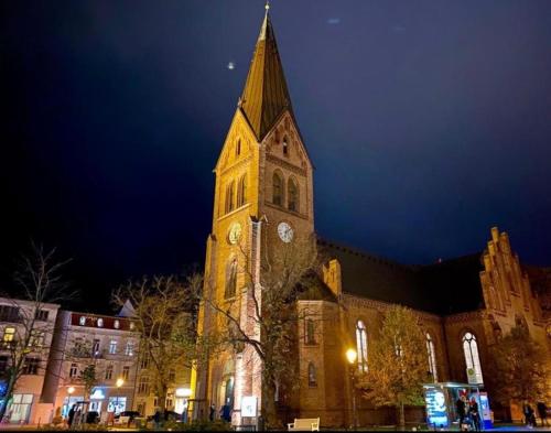 una chiesa con una torre dell'orologio di notte di Birnbom Warnemünde a Warnemünde