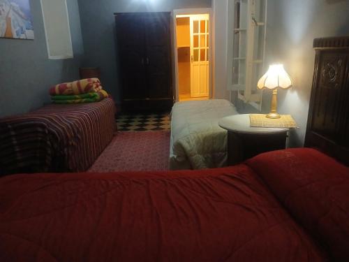 a bedroom with two beds and a table with a lamp at La Maison Haute Larache Morocco in Larache