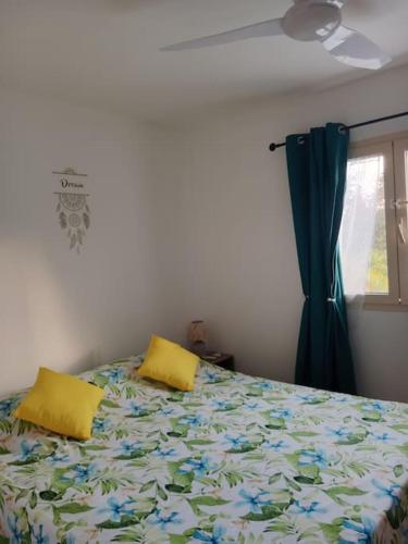 a bedroom with a bed with two yellow pillows at Au bout du rêve - Le Gosier in Le Gosier