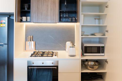 a small kitchen with a stove and a microwave at Apartment next to public station, BoxHill Central, 2 Bedrooms, free parking and wifi in Box Hill