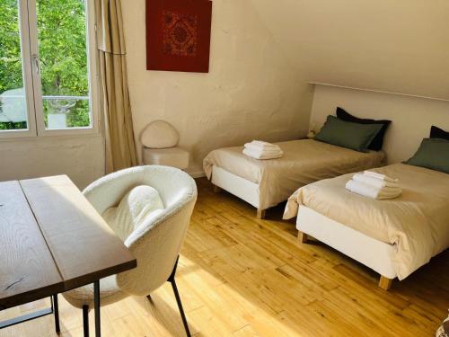 a room with two beds and a table and a chair at Villa Bellevue in Mailly-le-Château
