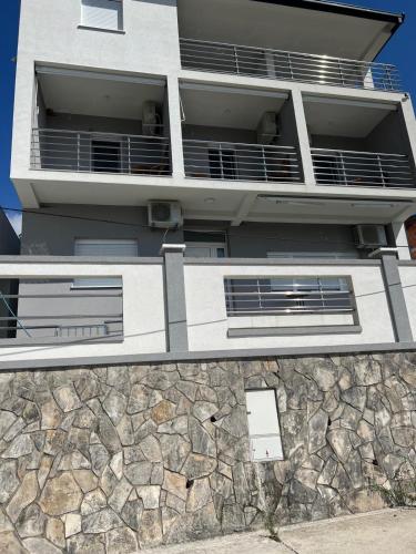 an apartment building with balconies and a stone wall at Vip apartmani in Tivat