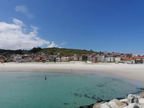 una persona in piedi in acqua sulla spiaggia di Apartamento Mar-Azul a Laxe