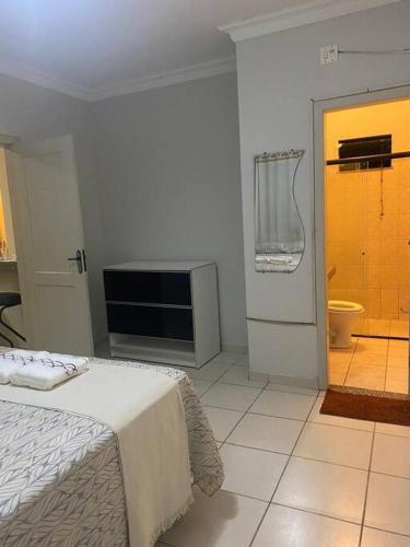 a bedroom with a bed and a tv and a bathroom at Apartamento Cidade Nova in Paragominas