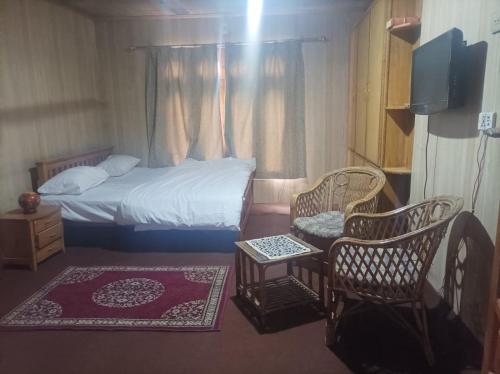 1 Schlafzimmer mit einem Bett und 2 Stühlen sowie einem TV in der Unterkunft Baltistan guest house in Skardu