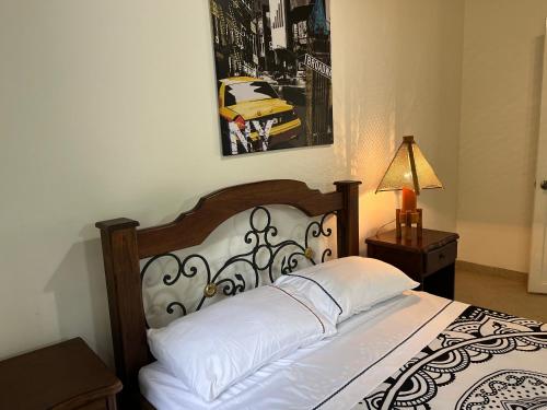 a bedroom with a bed with white sheets and a lamp at Finca Hotel San Miguel in Calarcá