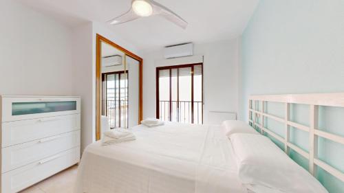 a white bedroom with a bed and a tv at El Olivo and Brisas Beach house in Gran Alacant