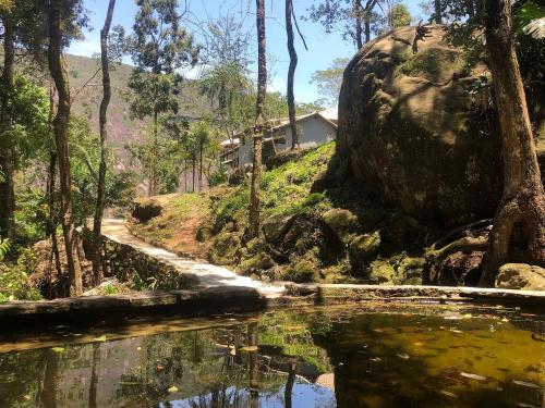 una casa en una colina junto a un cuerpo de agua en Quinta da Torre 7 suítes Cachoeira SPA aquecido, en Petrópolis