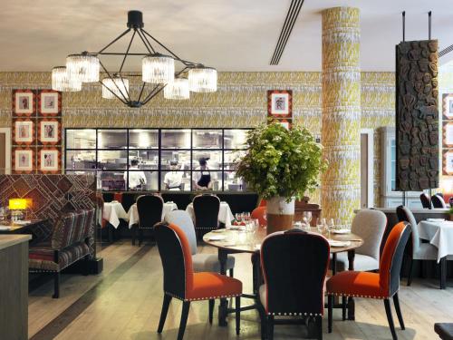 a dining room with tables and chairs and a bar at Ham Yard Hotel, Firmdale Hotels in London
