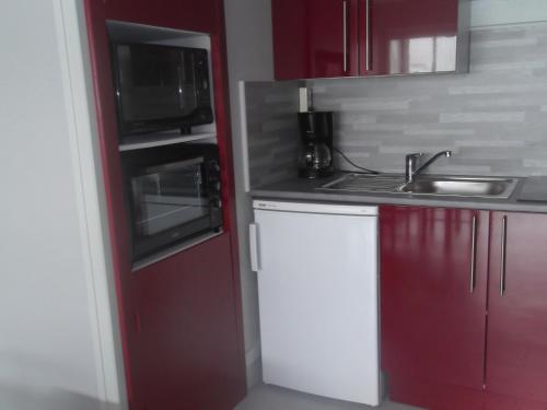 eine Küche mit roten und weißen Schränken und einem Waschbecken in der Unterkunft Les Mouettes St Hilaire in Saint-Hilaire-de-Riez
