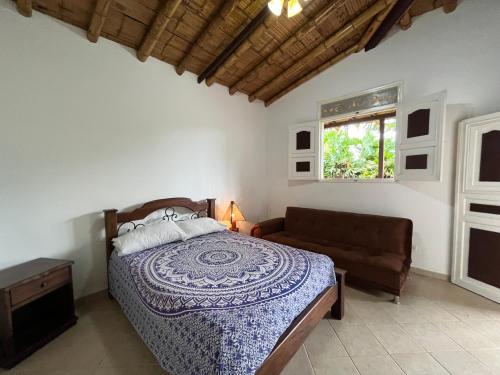a bedroom with a bed and a couch and a window at Finca Hotel San Miguel in Calarcá