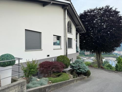 a white house with a garden in front of it at Veralto - Modern Suite with Como Lake view in Vacallo