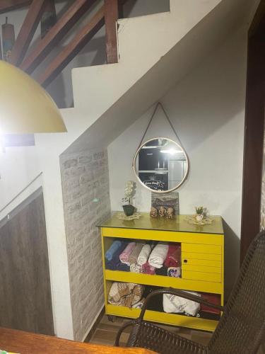eine gelbe Kommode mit einem Spiegel an der Wand in der Unterkunft Pousada Villa Del Bosque - Chalé Familiare in Camanducaia