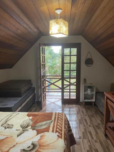 ein Schlafzimmer mit einem Bett und einem großen Fenster in der Unterkunft Pousada Villa Del Bosque - Chalé Familiare in Camanducaia