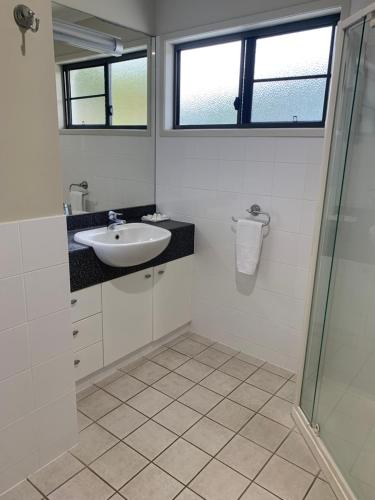 a bathroom with a sink and a glass shower at Island Views in Airlie Beach