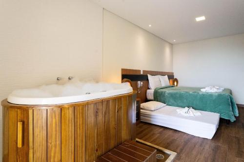 a bathroom with a bath tub and a bed at Pousada Cantareira - Suítes na Serra da Cantareira in Mairiporã
