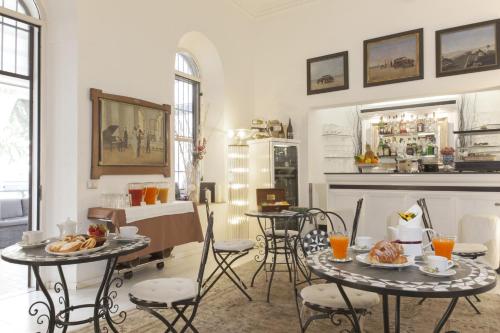 sala de estar con 2 mesas, sillas y chimenea en Villa Pirandello en Roma