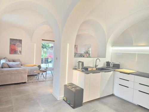 a kitchen with white cabinets and a living room at Design I Gewölbe I sanierter Pferdestall I EuropaPark I Boxspring I Nespresso I Terrasse I Parkplatz in Kippenheim