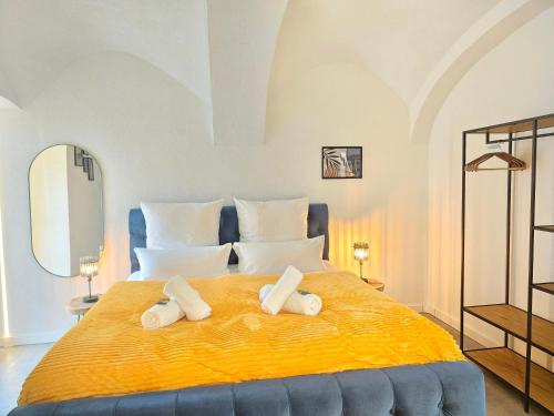 基彭海姆Design I Gewölbe I sanierter Pferdestall I EuropaPark I Boxspring I Nespresso I Terrasse I Parkplatz的一间卧室配有一张大黄床和2条毛巾
