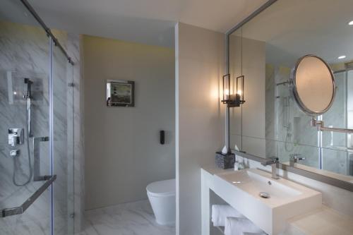 a white bathroom with a sink and a mirror at Hotel IKON Phuket - SHA Extra Plus in Karon Beach
