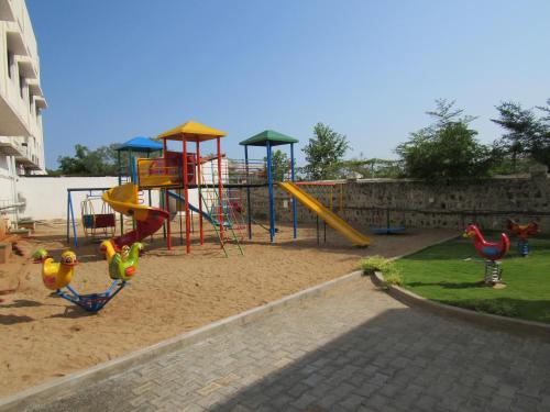 a playground with a slide and play equipment in a yard at Grand Serenaa Hotel & Resorts, Auroville in Auroville