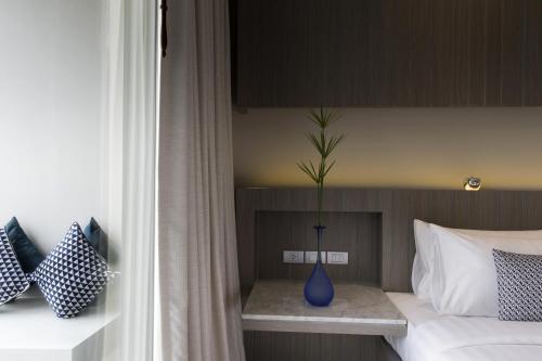 a blue vase sitting on a table next to a bed at Hotel IKON Phuket - SHA Extra Plus in Karon Beach