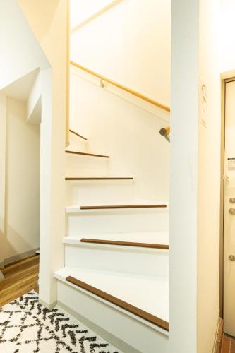 a hallway with stairs with a rug at 18, Oji B, Detached house for rent, 王子B in Tokyo
