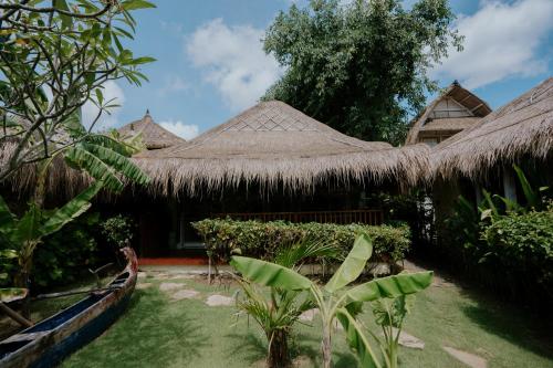 a resort with a grass roofed building with a yard at Le Yanandra Bali Resort in Jimbaran