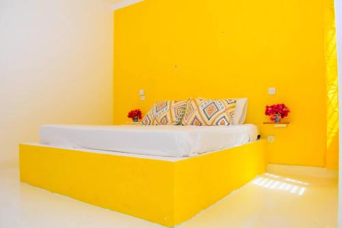Cette chambre jaune comprend un lit avec un mur jaune. dans l'établissement Shoreline Serenity in Malindi, à Malindi