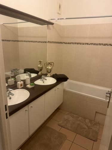 une salle de bain avec deux lavabos et une baignoire dans l'établissement Stade de France métro RER, à Aubervilliers